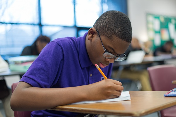 Student writing in desk