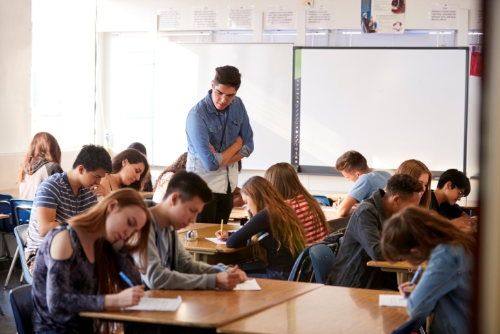 high school teacher inspecting class